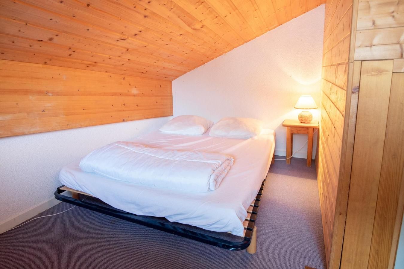 Un dormitorio con una cama, una mesita de noche y una lámpara.