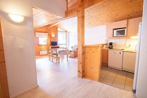 A wooden interior with a dining area, kitchen, and a visible living space.