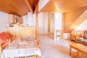 Una habitación acogedora con suelo de madera, una mesa de comedor, sillas y un banco.