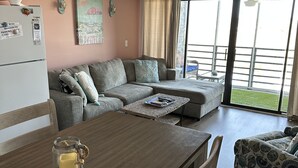 A cozy living area with a wooden dining table, a sofa, and a ceiling fan. - Garden City Beach- Great Location! 2 minute walk to beach and pier! Sleeps 6.  (Murrells Inlet)
