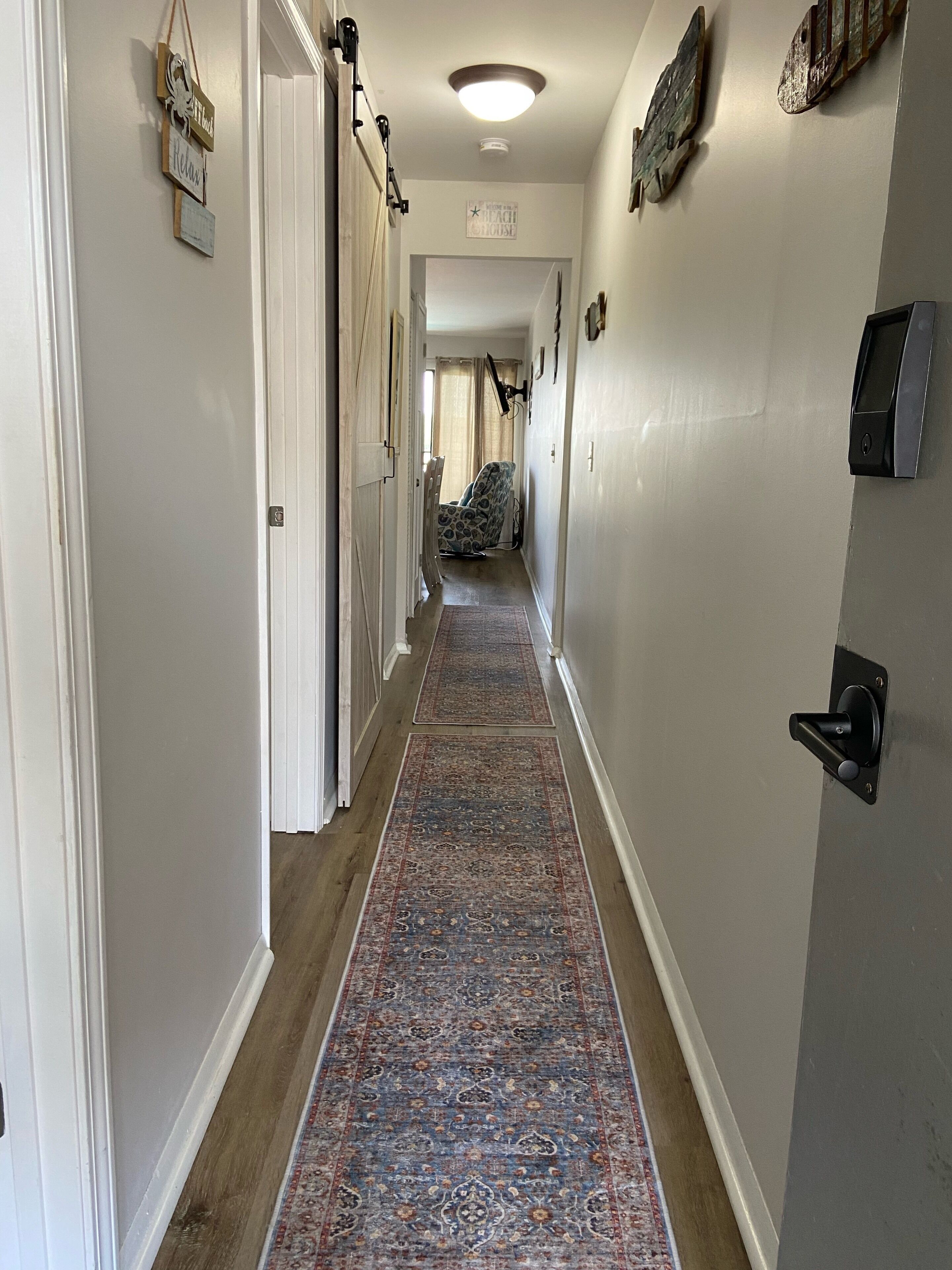 A hallway with a patterned carpet, a chair, and wall-mounted decorations.
