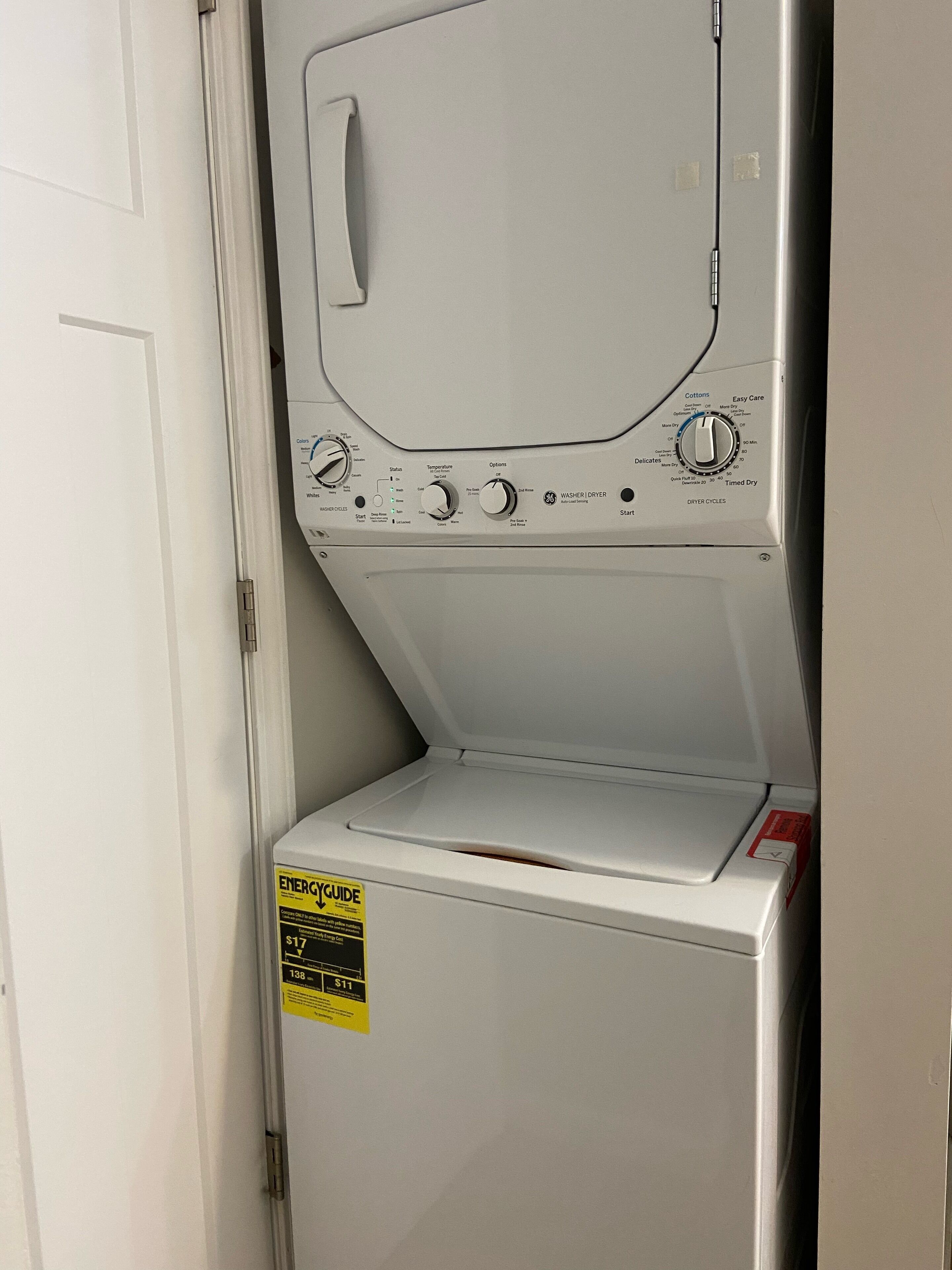 A front view of a white washing machine with control knobs and a yellow energy guide sticker.