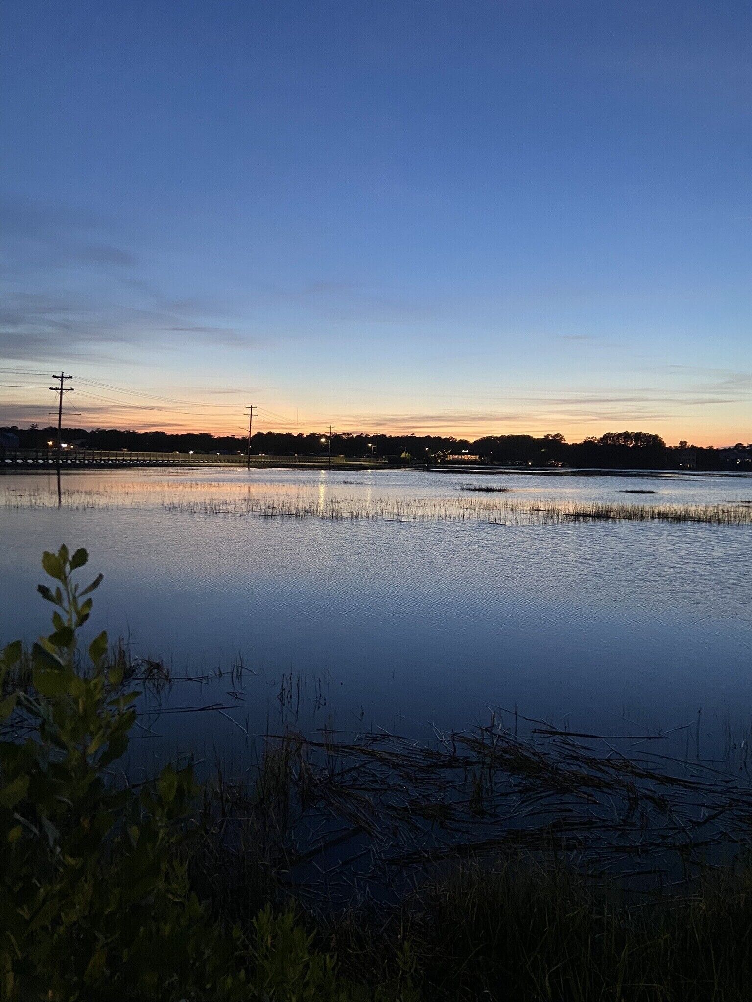 Een kalem wateroppervlak met een heldere lucht bij zonsondergang.
