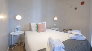 A hotel room with a bed, two bedside tables, a small round table, and a chair. - Sweett | Torre Velasca I (Milano)