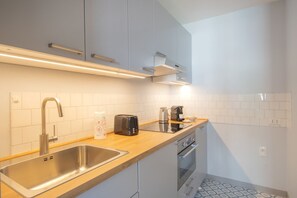 A modern kitchen with a stainless steel sink, a coffee maker, and a toaster on the countertop. - Sweett | Torre Velasca VII (Milano)
