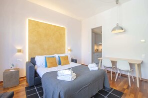 A modern hotel room with a large bed, bedside lamps, a desk, and a chair. - Sweett | Torre Velasca VII (Milano)