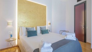 Una habitación de hotel con una cama grande, dos mesitas de noche, un armario y una puerta.