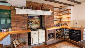 Une cuisine avec un mur en briques, des étagères en bois et une cuisinière.