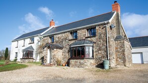 Une maison en pierre avec un toit en pente, de nombreuses fenêtres et une cheminée.