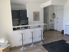 A modern kitchen with a central island, bar stools, and a dining area.