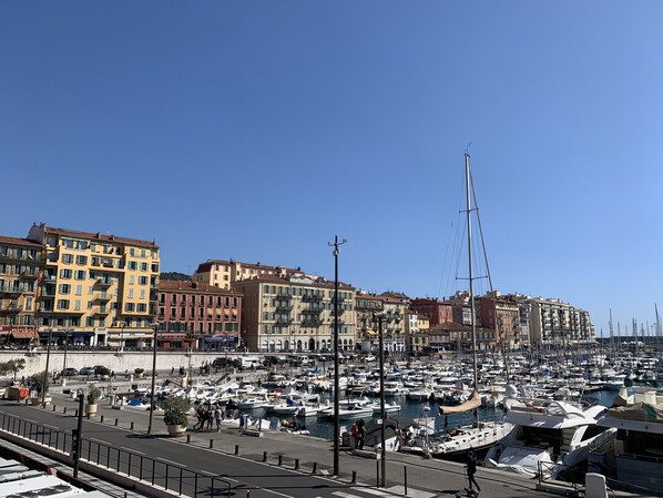 A marina with numerous boats docked, surrounded by multi-story buildings with balconies.