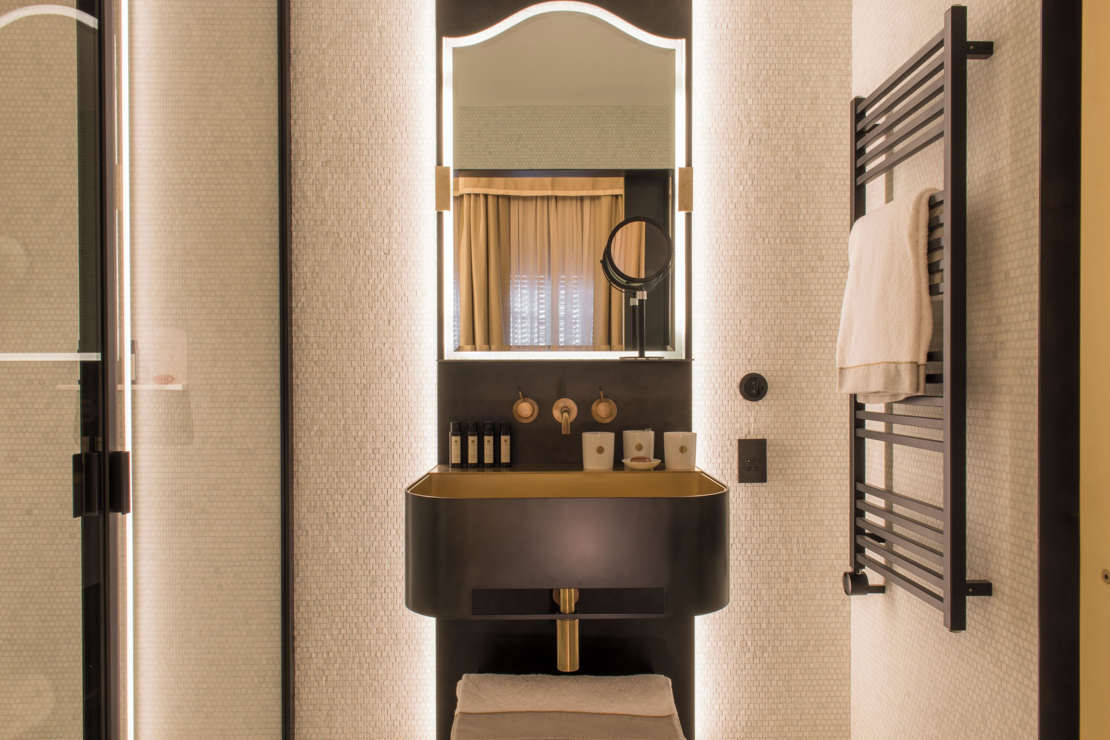Une salle de bain avec un lavabo noir, un miroir et un porte-serviettes.