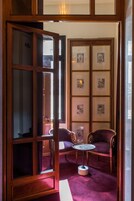Ein Zimmer mit Holztür, Bildergalerie in Rahmen, zwei Stühlen und einem kleinen Tisch.