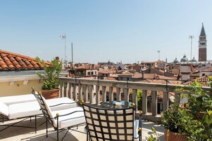 Terraço com mesa e cadeiras, vista para um horizonte urbano com edifícios e uma torre.