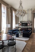 A spacious living room with a large chandelier, a television, and a bookshelf.
