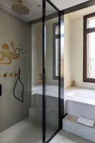 Uma casa de banho moderna com chuveiro em cabine de vidro, um espelho grande e uma banheira branca.