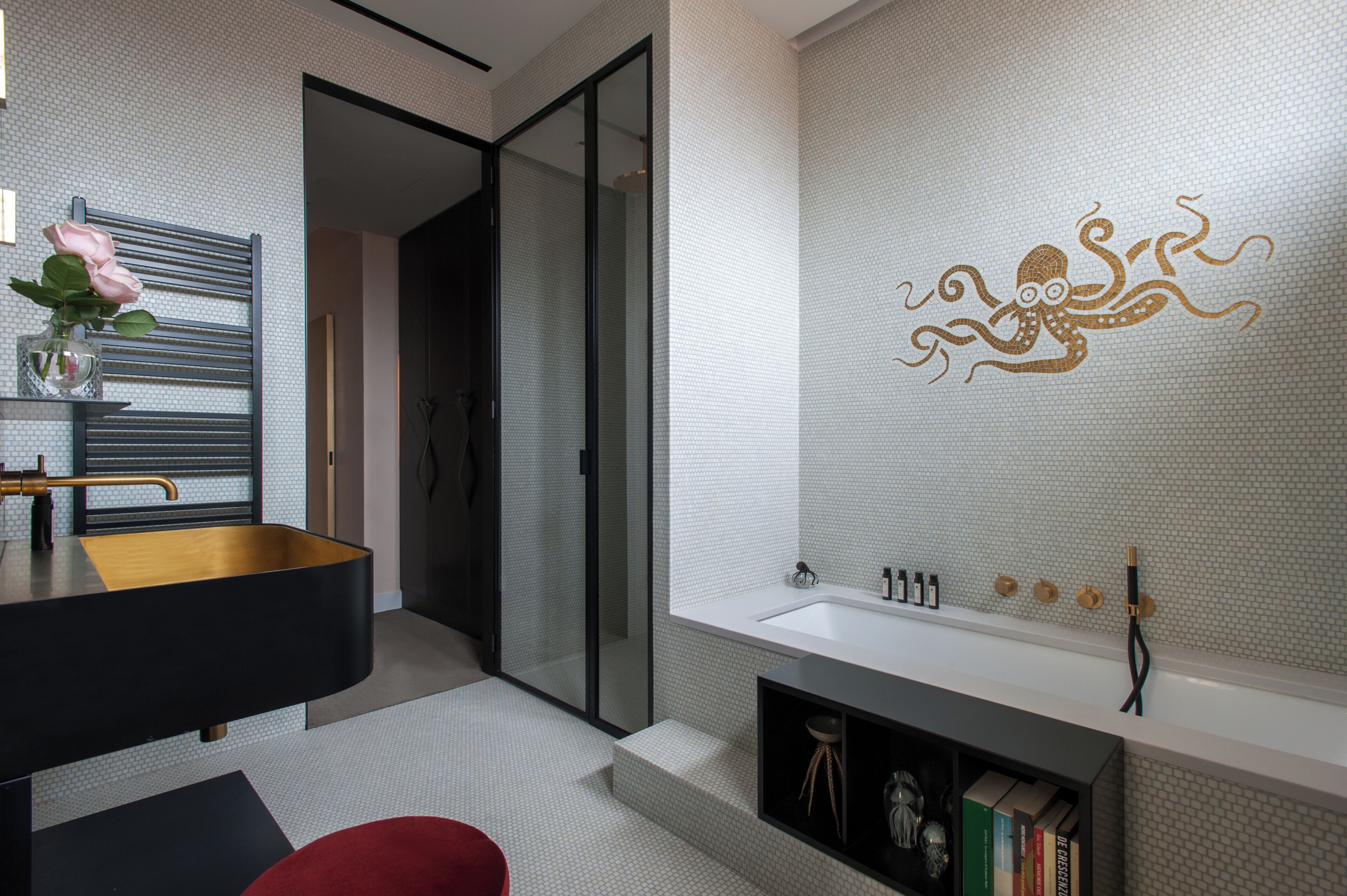 A modern bathroom with a black vanity, a white sink, and a glass shower enclosure.