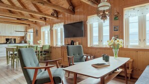 L’intérieur d’un chalet en bois comprend un coin repas, des murs en bois, un téléviseur à écran plat et une grande fenêtre offrant une vue panoramique.