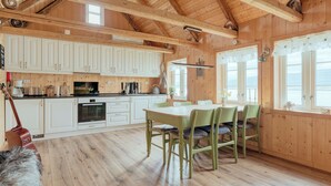 Un intérieur en bois comprenant un coin repas, une cuisine et de grandes fenêtres.
