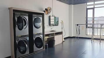 Una lavandería con cuatro lavadoras, un lavabo y una ventana que proporciona luz natural.