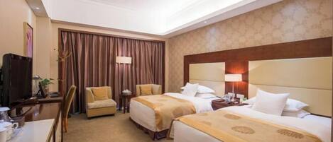 A hotel room with two beds, a desk, a chair, a TV, and a window with curtains.