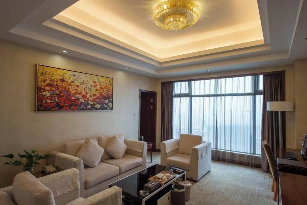 A modern living room with a sofa set, a coffee table, and a large window with curtains.