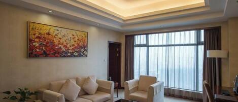A modern living room with a sofa set, a coffee table, and a large window with curtains.