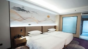 Quarto de hotel com uma cama grande, uma mesinha de cabeceira, televisão na parede e uma janela ampla.