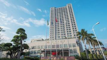 Een hoog hotel met een moderne gevel, een wapperende vlag en een verzorgde tuin.