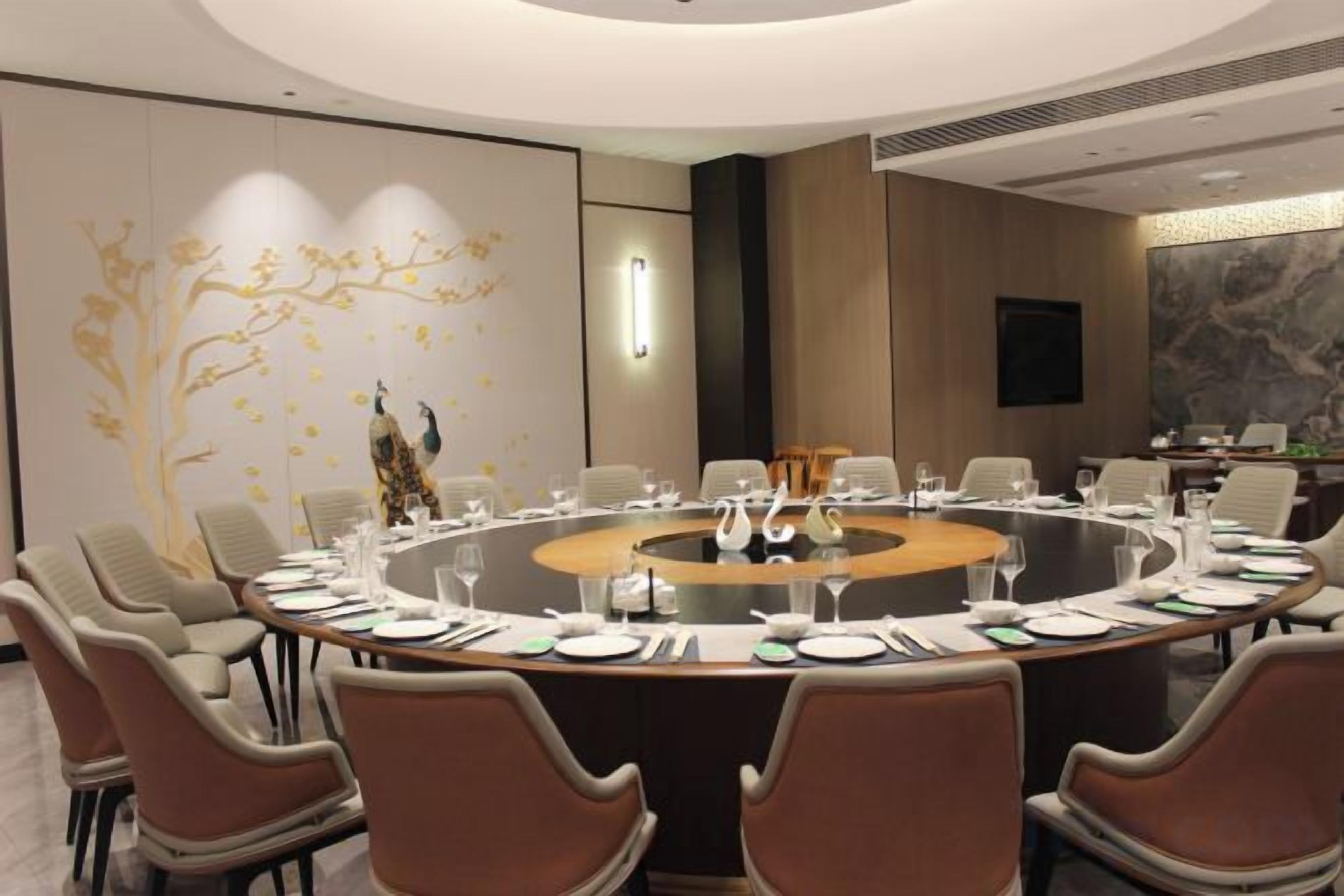 Un salón de conferencias con una mesa redonda, sillas y una decoración de pared.