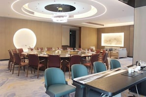 Une salle de conférence équipée d’une table ronde, de chaises et d’un grand écran.