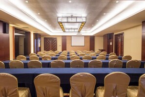 A conference room with rows of tables and chairs, a projector screen, and a presentation screen. - Landscape Hotel (Zhangping)