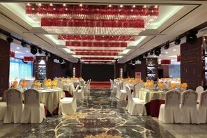 A banquet hall with round tables, white chairs, and a central stage.