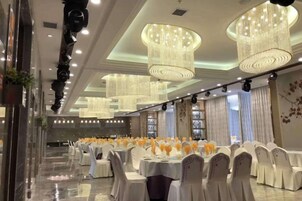 Un salón de banquetes con varias mesas redondas, manteles blancos y sillas.