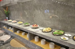 Un bufé con diferentes alimentos dispuestos sobre una barra de mármol.