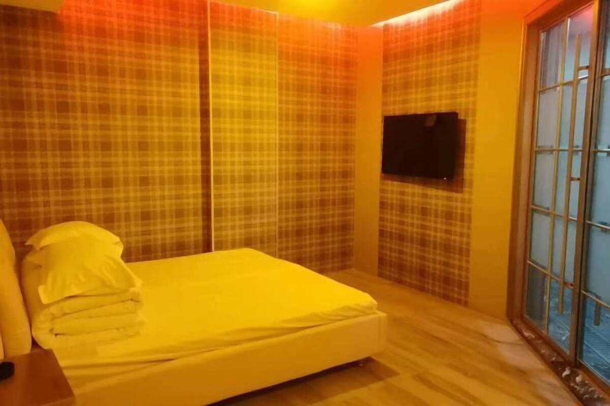 Ein Schlafzimmer mit Bett, Vorhängen, Fernseher und Fenster.
