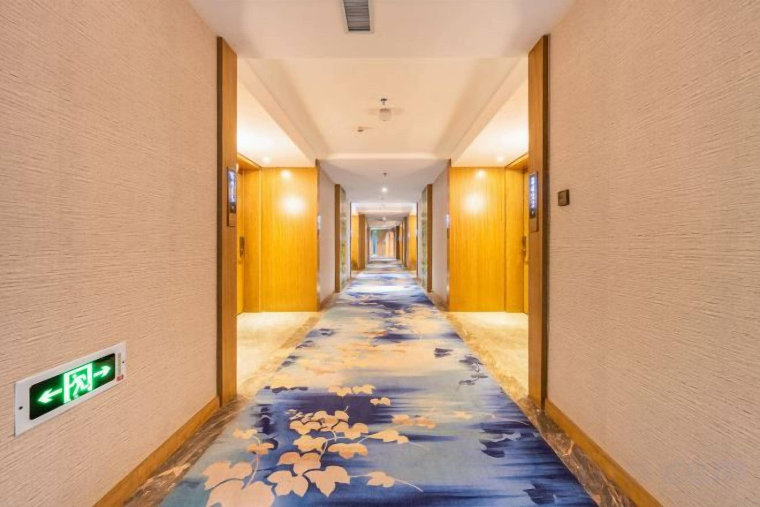 A hotel corridor with a carpeted floor, wooden walls, and a ceiling light fixture.