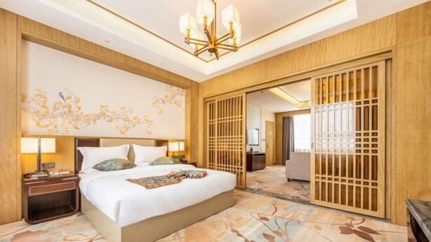 Une chambre d’hôtel avec un grand lit, une table de chevet avec une lampe, un mur décoratif et une cloison en bois.