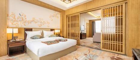 Una habitación de hotel con una cama grande, paneles de madera, una araña y una alfombra floral.