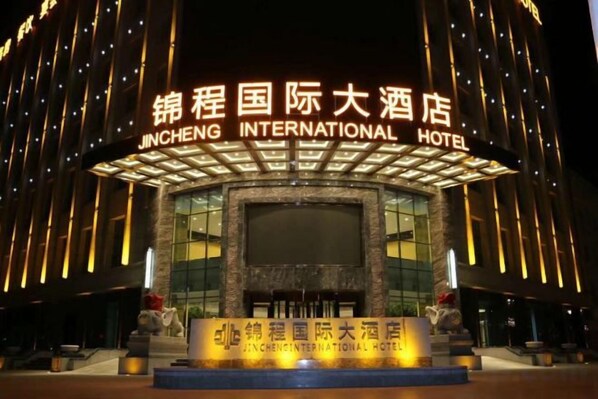 The exterior of the Jincheng International Hotel with illuminated signage and a central entrance.