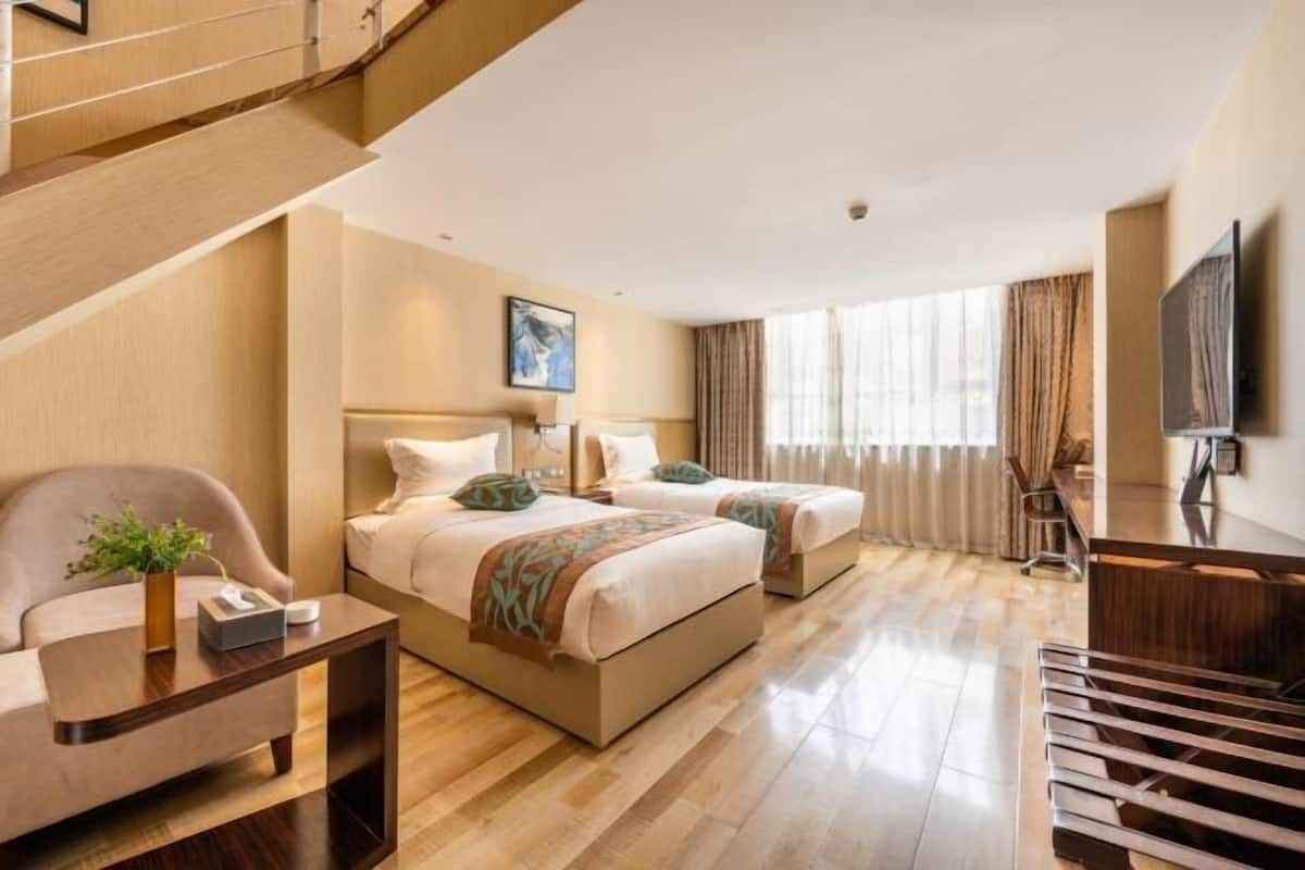 Ein Hotelzimmer mit Treppe, zwei Betten, einem Schreibtisch und einem Fernseher.