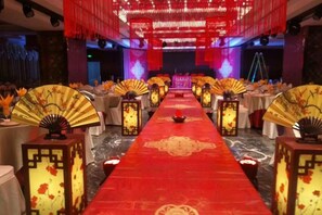 A banquet hall with a red carpet, tables with white tablecloths, and traditional lanterns.