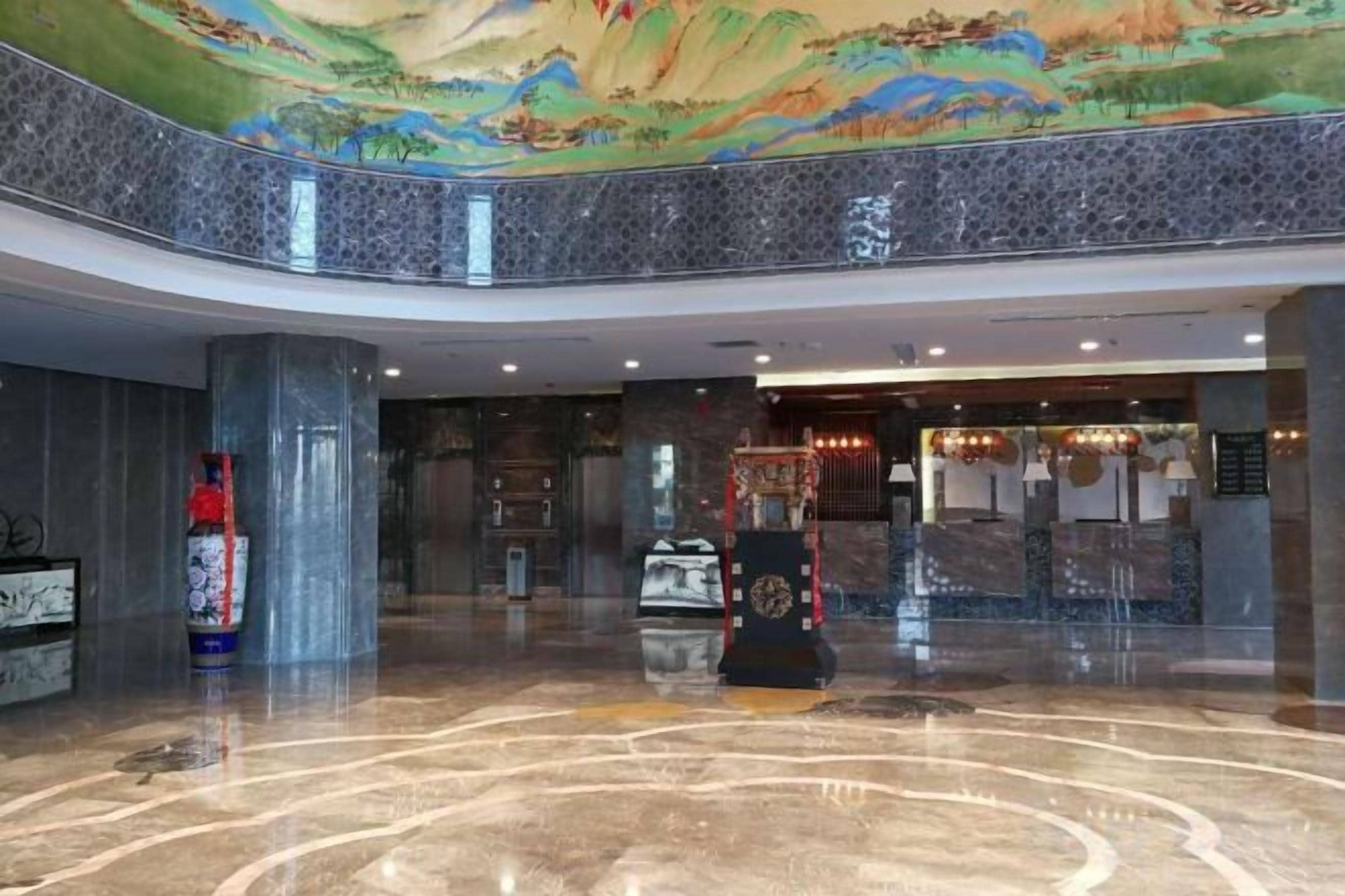 A lobby with a high ceiling, a marble floor, and a mural.