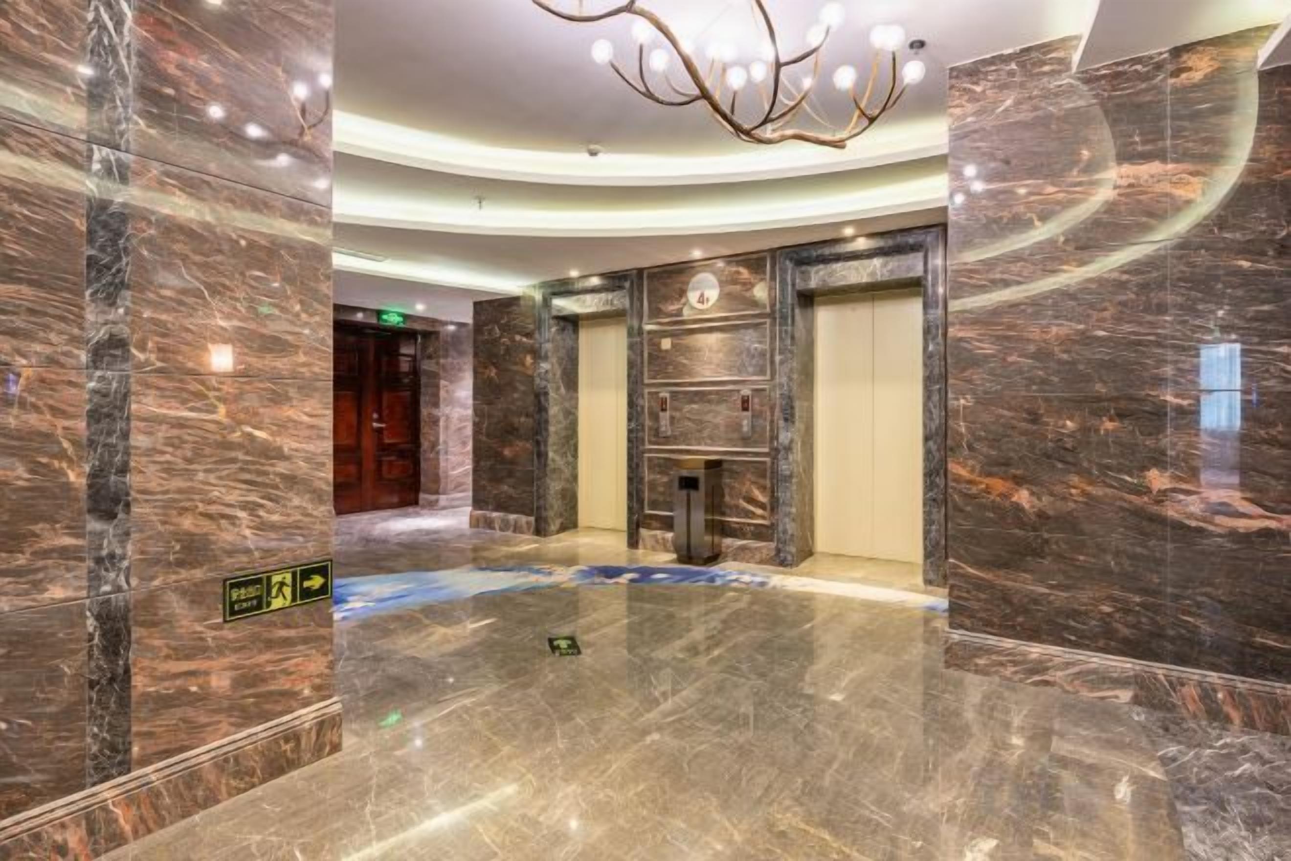 A spacious lobby with marble flooring, a chandelier, and a reception desk.