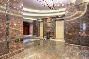 Eine geräumige Lobby mit Marmorböden, einem Chandelier und einem Empfangsbereich.