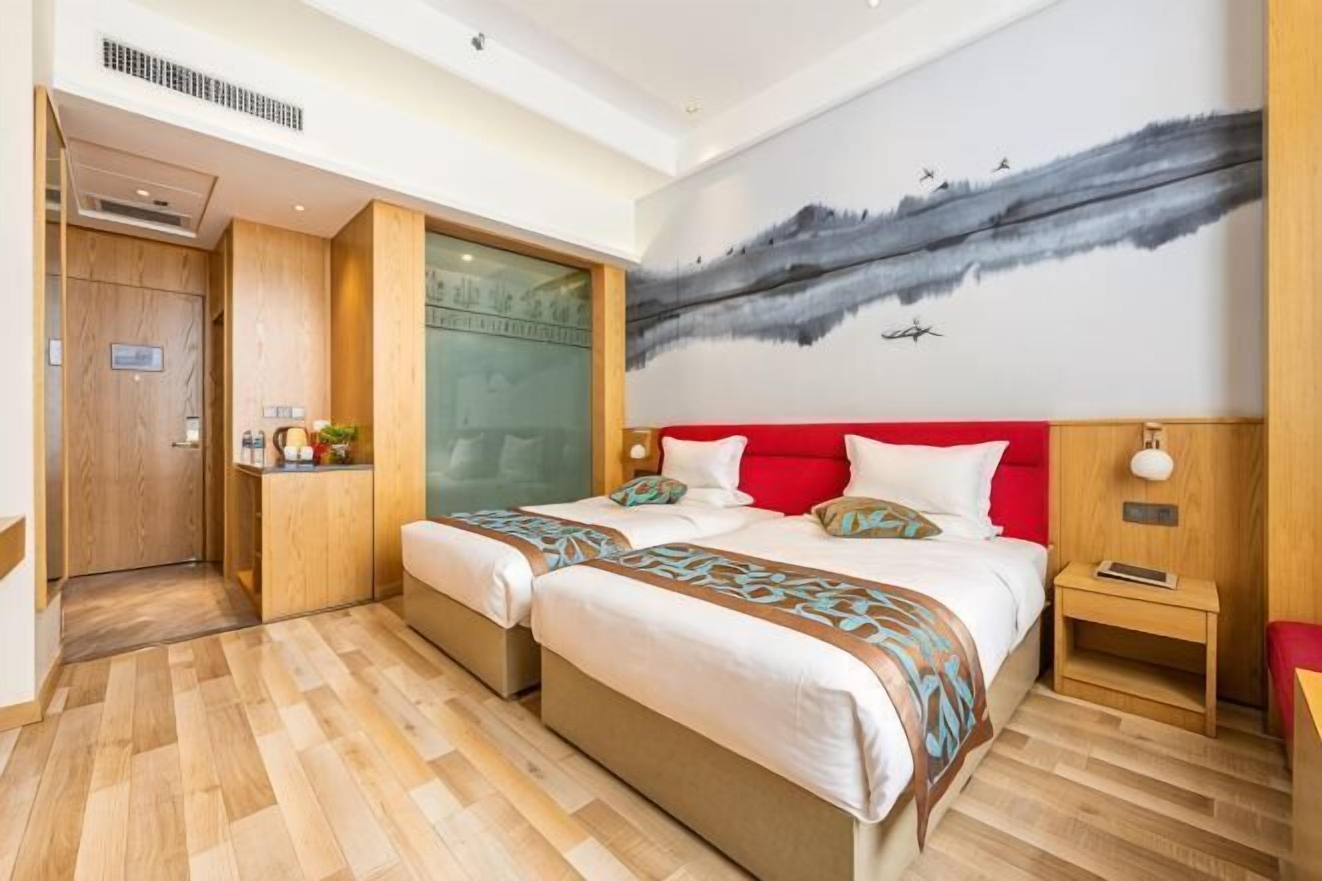 A hotel room with a large bed, a small bedside table, a nightstand, a wooden wardrobe, and a painting on the wall.