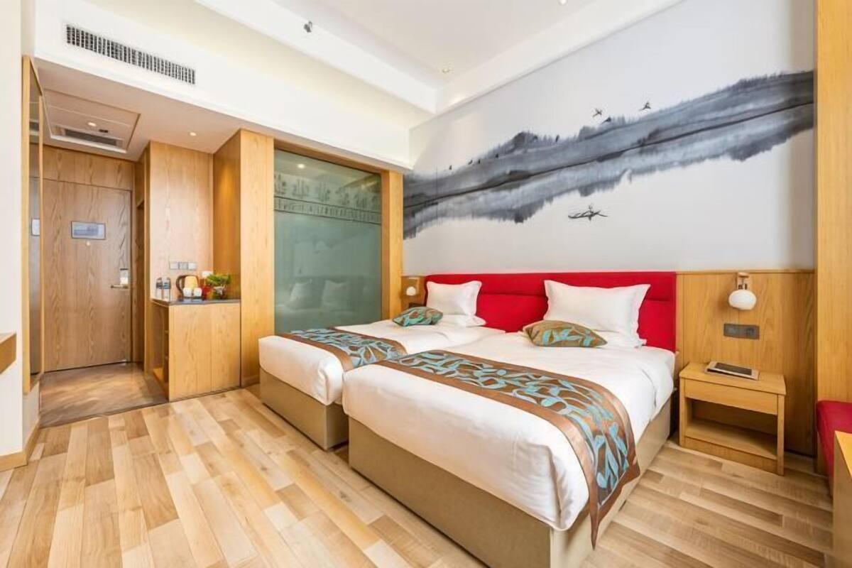 Ein Hotelzimmer mit einem großen Bett, einem kleinen Nachttisch, einem Schrank und einem Bild an der Wand.