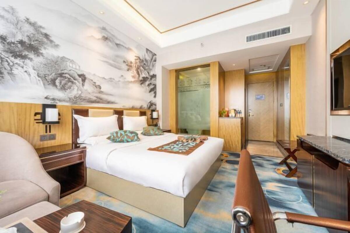 Ein Hotelzimmer mit einem großen Bett, einem Schreibtisch, einem Sessel, einer Couch und einem Bild an der Wand.