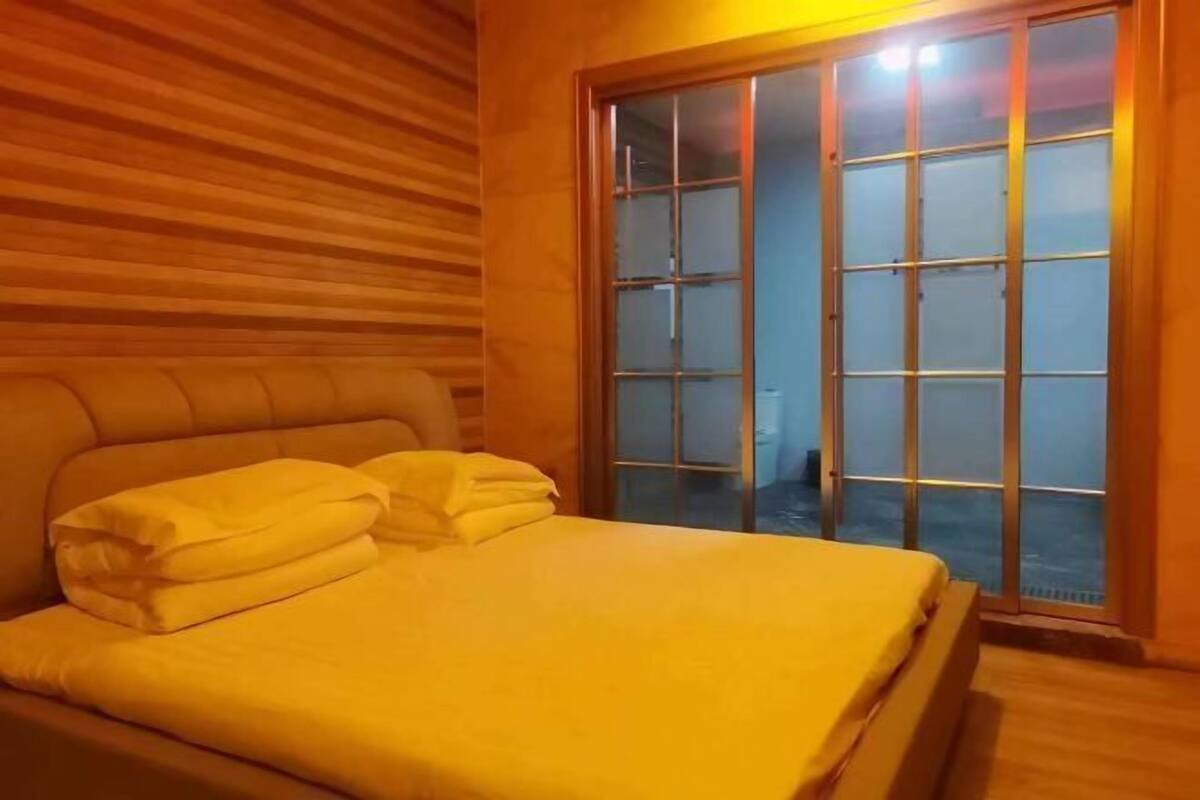 Ein Zimmer mit einem Bett, einem Holzkopfteil und einer Schiebetür zum Balkon.