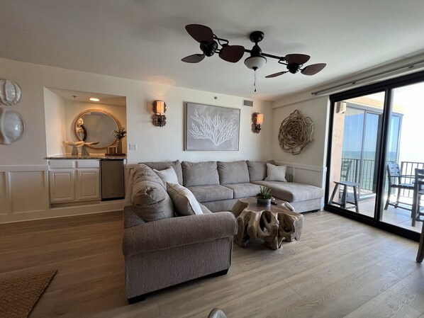 A modern living room with a sectional sofa, a wooden coffee table, and a ceiling fan.